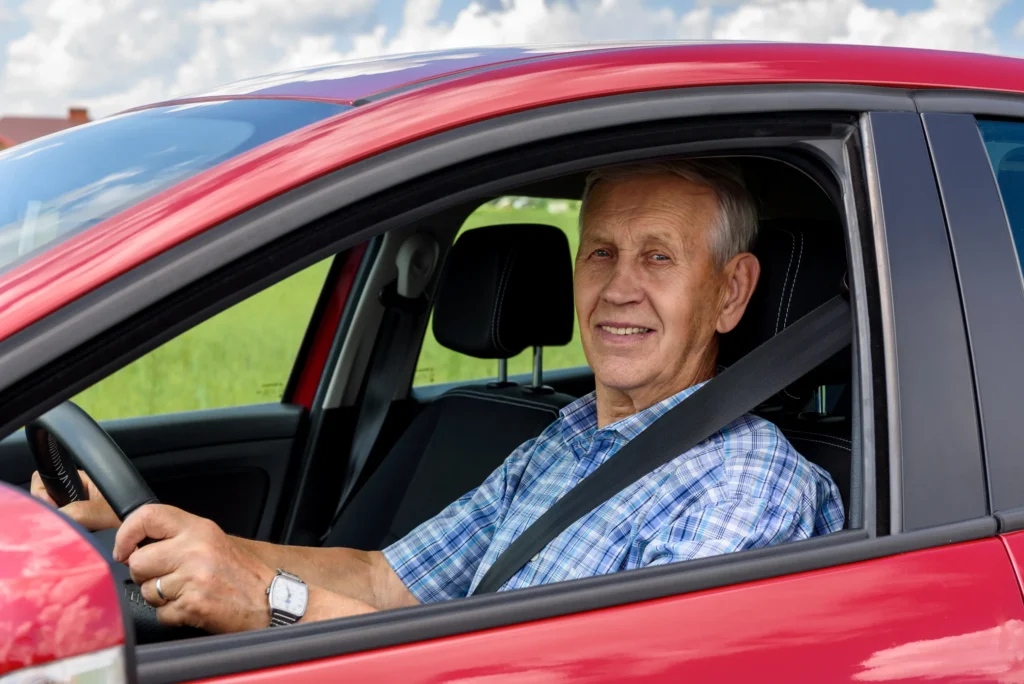 Older man driving a red car