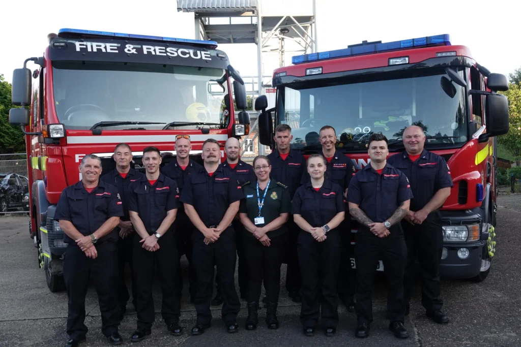 Firefighters and Ambulance Personnel standing in front of two Fire Service Vehicles.
