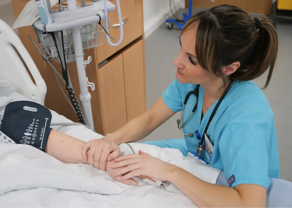 Medical Personnel holding a patients hand at their bedside.