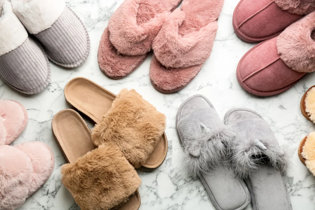 A variety of colourful fluffy slippers, sat on a white carpet