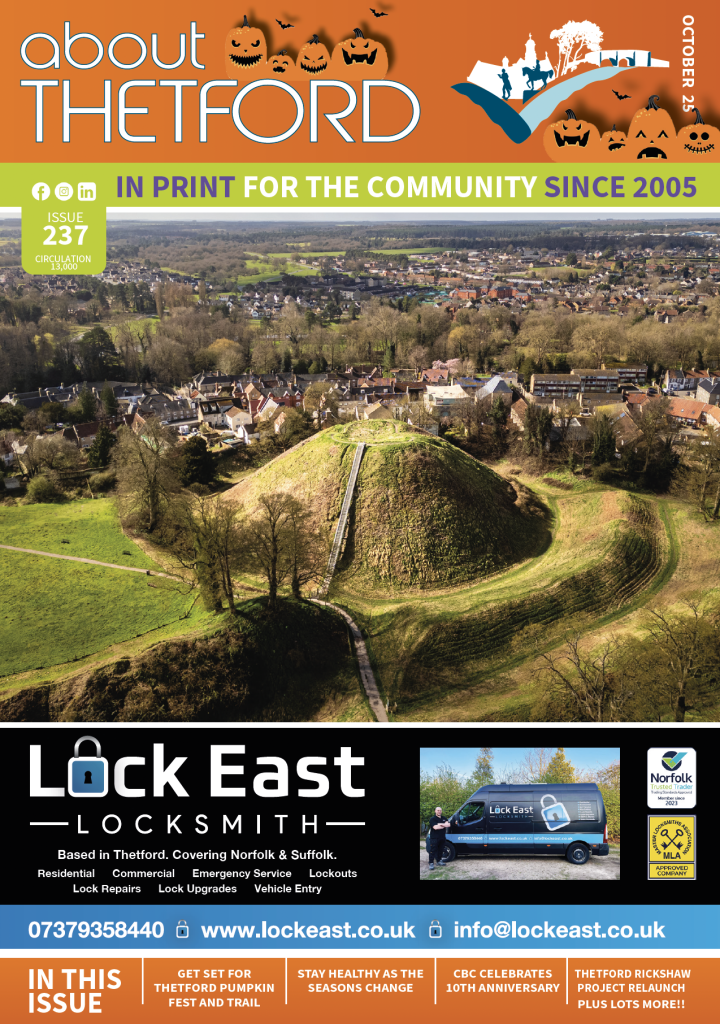 Front cover of About Thetford magazine, October 2025 edition. The header has an orange Halloween-themed design with pumpkins and bats, alongside the magazine’s logo. The main cover photo — winner of the Thetford Calendar Competition — shows an aerial view of Thetford Castle mound surrounded by houses and countryside. At the bottom is a black advert panel for Lock East Locksmith, featuring their logo, contact details, van, and accreditation badges. A footer strip lists highlights inside the issue: Thetford Pumpkin Fest and Trail, staying healthy as the seasons change, CBC’s 10th anniversary, the Rickshaw Project relaunch, plus more.