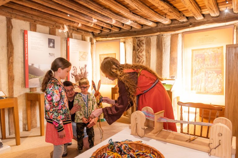 Two children and an adult take part in a hands-on activity inside Ancient House Museum, with wooden tools and colourful materials laid out on a table, demonstrating a family-friendly workshop setting.