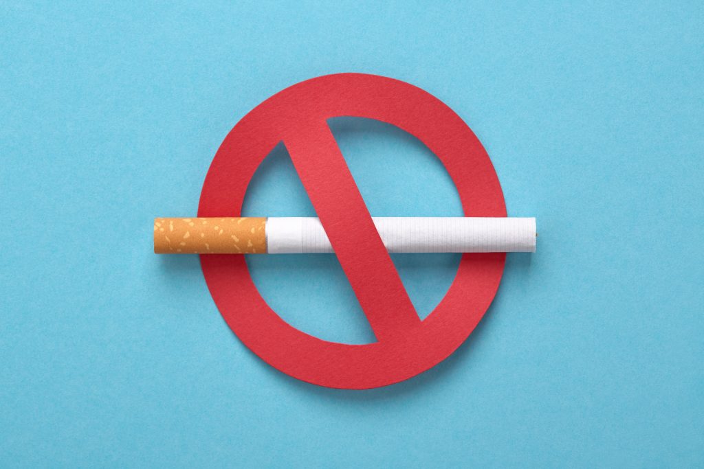 A cigarette placed across a red “no smoking” symbol on a blue background, representing a ban on smoking or a stop-smoking message.