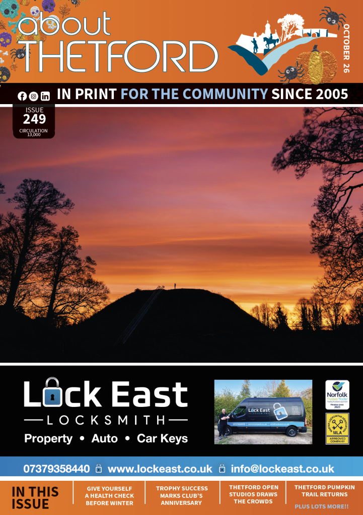 October 2026 cover of About Thetford Magazine, Issue 249. The main image shows a vivid orange, pink and purple sunset over Castle Hill in Thetford, with the ancient earthwork and surrounding trees silhouetted against the sky and a lone figure visible at the summit. The orange masthead is decorated with autumn flowers, leaves, spiders and a pumpkin. Below the cover image is an advert for Lock East Locksmith, while cover lines highlight a winter health check, a local club’s trophy success, Thetford Open Studios and the return of the Thetford Pumpkin Trail.